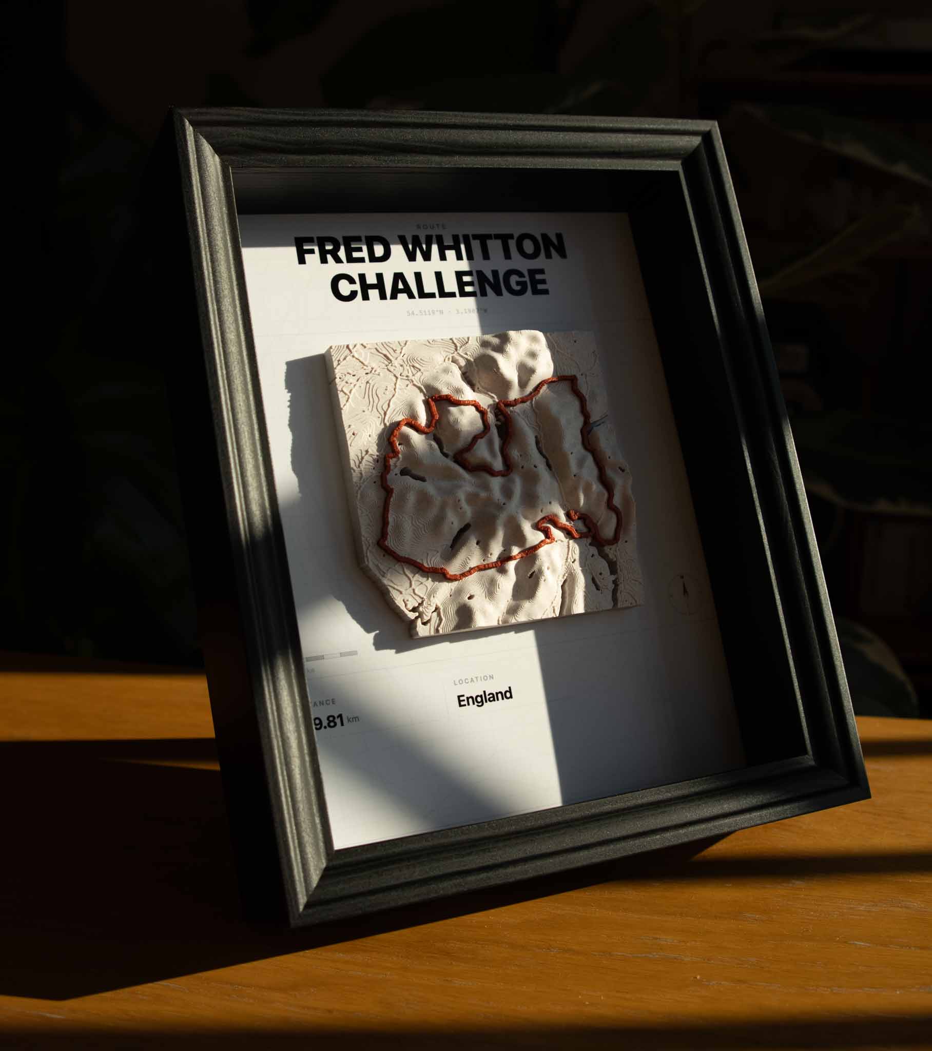 Custom 3D printed topographic map of a cycling route in a black wood frame